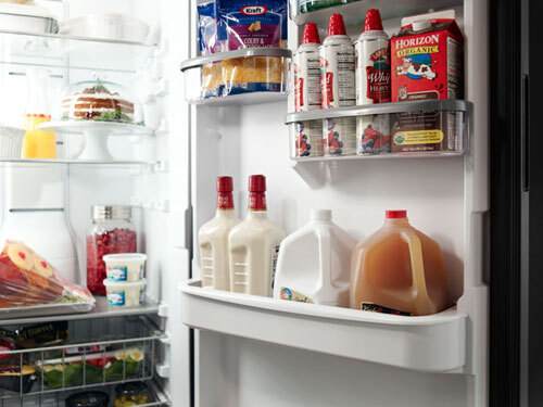 Open garage refrigerator stocked with beverages, bulk groceries, and meal prep items.